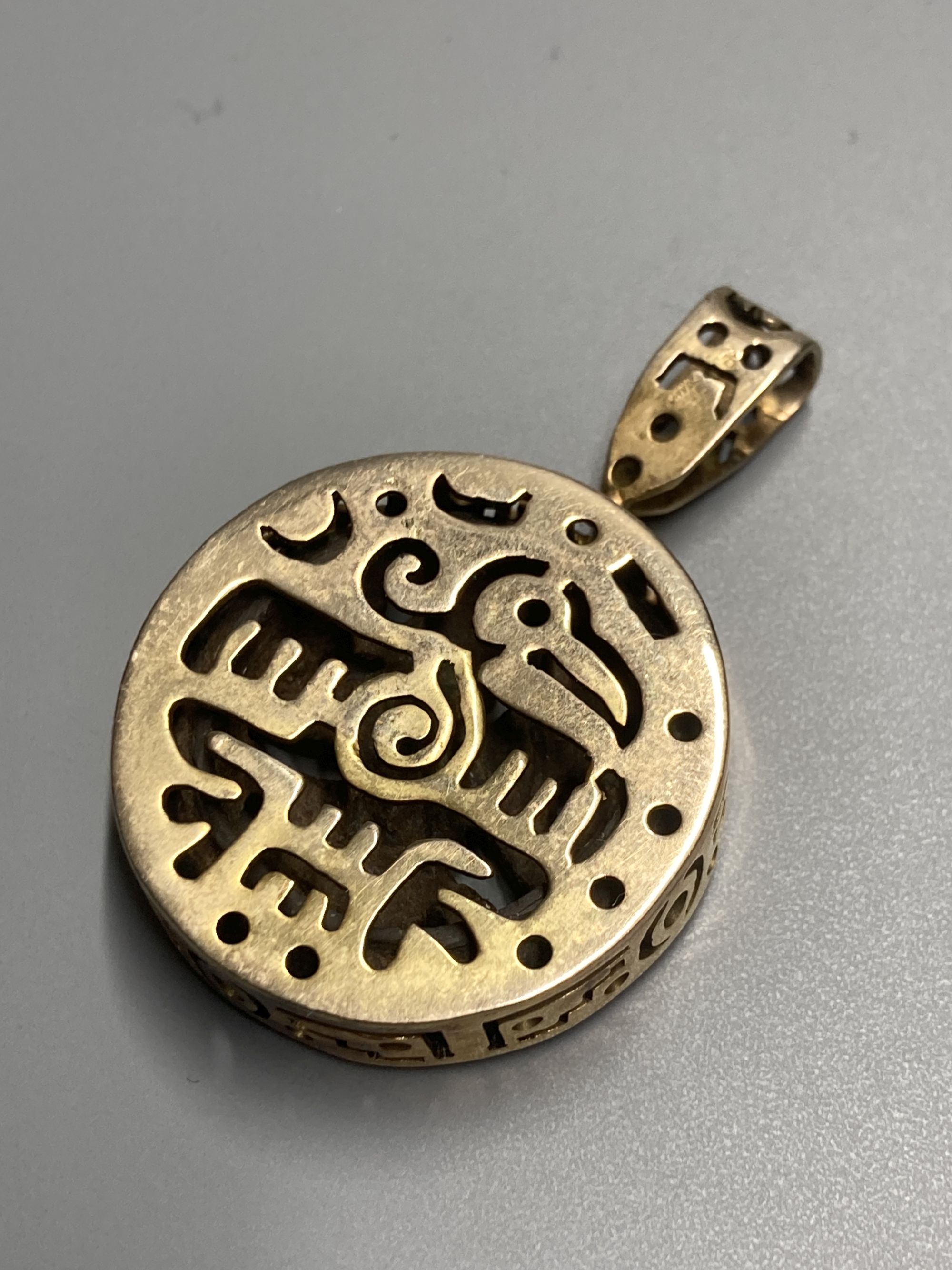 An unusual Chinese pierced gilt metal and base metal inset ring, size P, and matching pendant, overall 53mm.